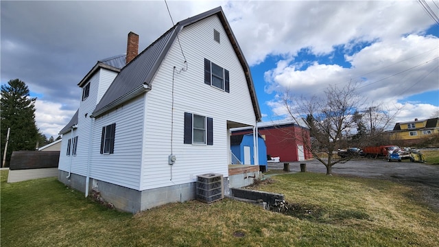 rear view of house featuring central AC and a lawn