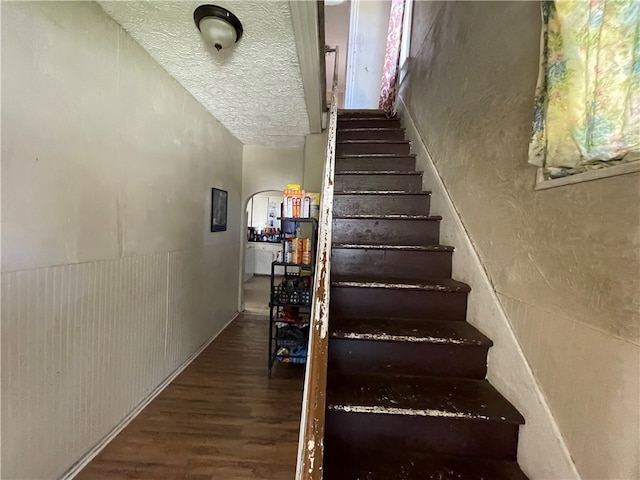 stairway featuring a textured ceiling and hardwood / wood-style floors