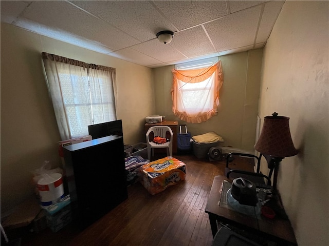 living area with a drop ceiling and hardwood / wood-style floors