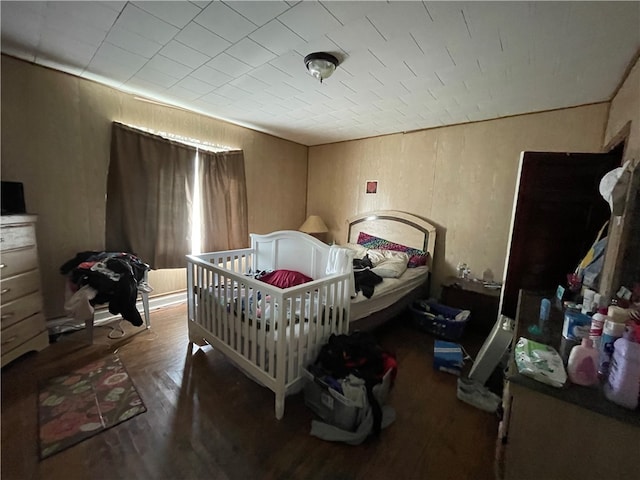 bedroom with a nursery area and dark hardwood / wood-style flooring