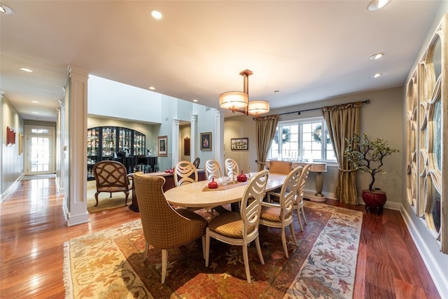 dining room featuring light hardwood / wood-style flooring, decorative columns, and an inviting chandelier