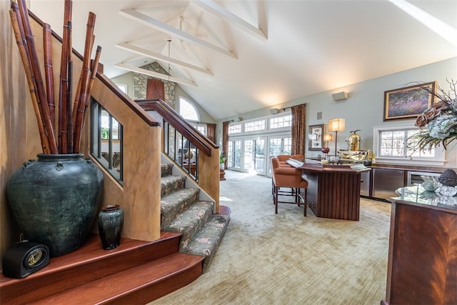 stairway featuring light colored carpet, high vaulted ceiling, and a wealth of natural light