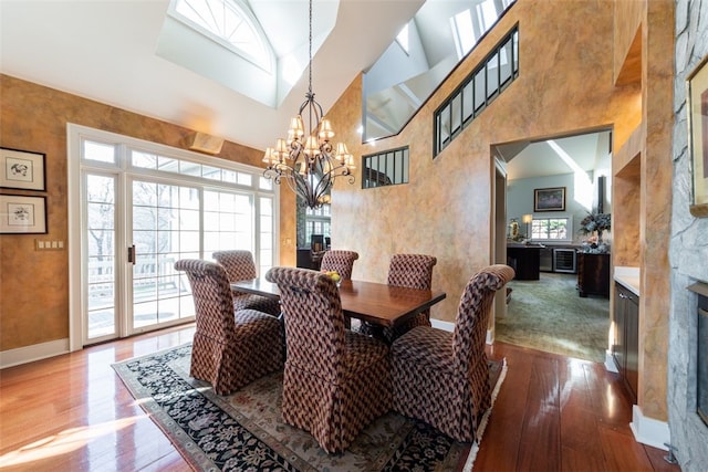 dining area featuring high vaulted ceiling, hardwood / wood-style floors, a healthy amount of sunlight, and a chandelier