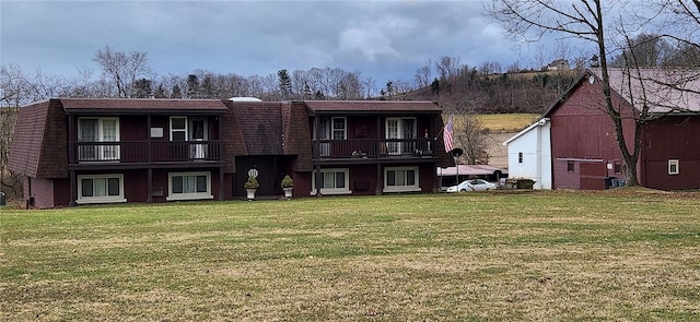 view of property featuring a balcony and a front yard