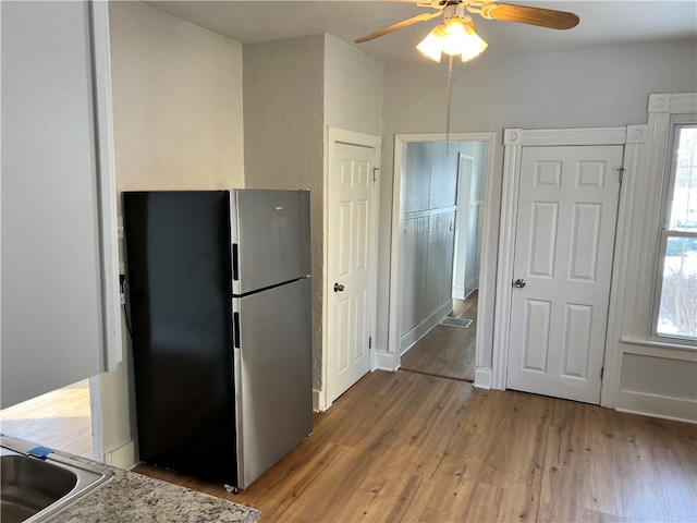 kitchen with stainless steel refrigerator, ceiling fan, and hardwood / wood-style floors