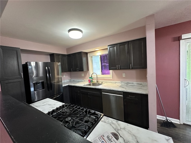 kitchen featuring dark hardwood / wood-style floors, appliances with stainless steel finishes, light stone countertops, and sink