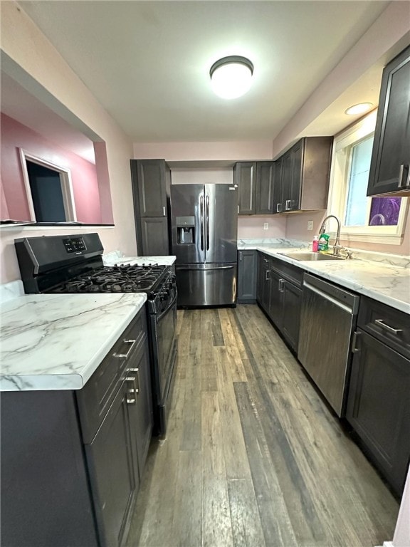 kitchen featuring sink, appliances with stainless steel finishes, light stone countertops, and light hardwood / wood-style flooring