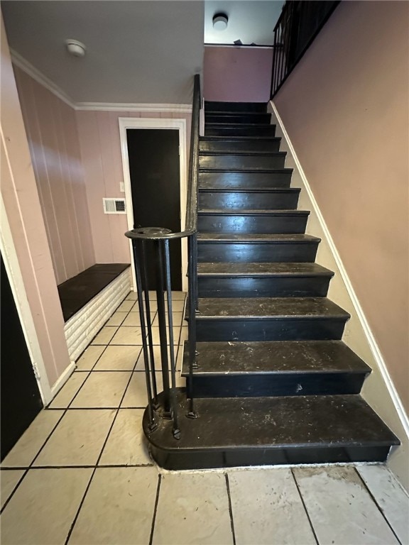 staircase with ornamental molding and light tile floors