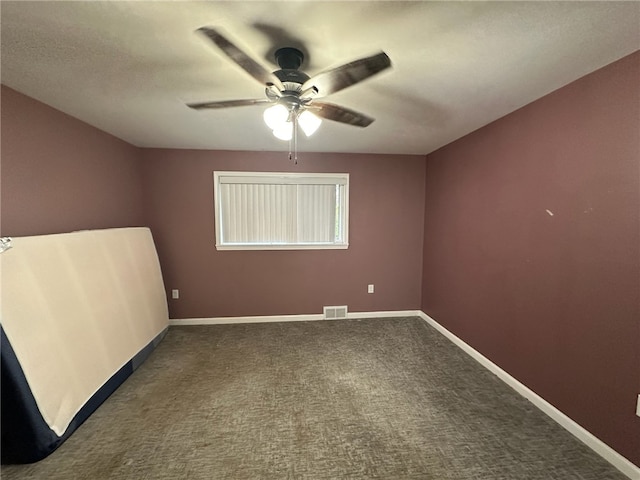 spare room featuring dark carpet and ceiling fan