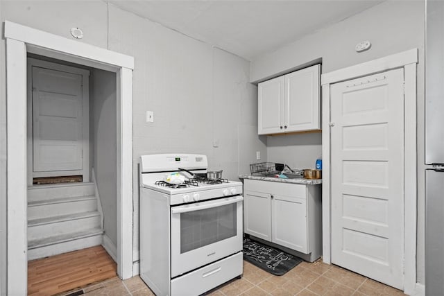 kitchen with light hardwood / wood-style flooring, white cabinets, and white gas stove