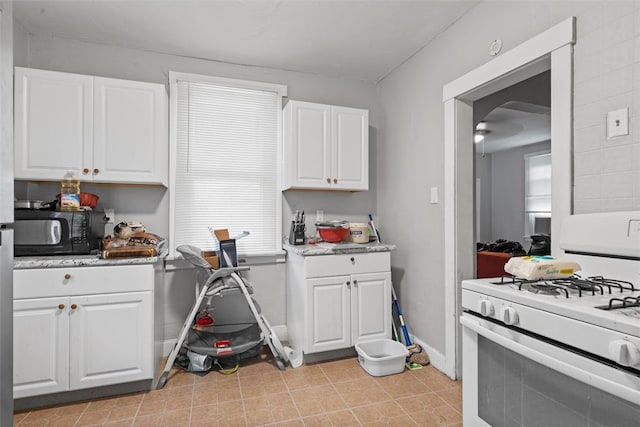 kitchen with light tile floors, ceiling fan, white cabinetry, and white range with gas stovetop