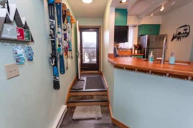 kitchen with green cabinets, stainless steel refrigerator, rail lighting, and a baseboard heating unit