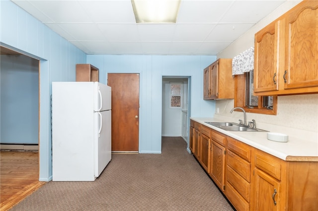 kitchen featuring hardwood / wood-style flooring, white refrigerator, baseboard heating, and sink