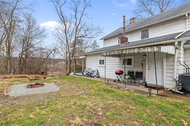 back of property with an outdoor fire pit, central AC unit, a lawn, and a patio area