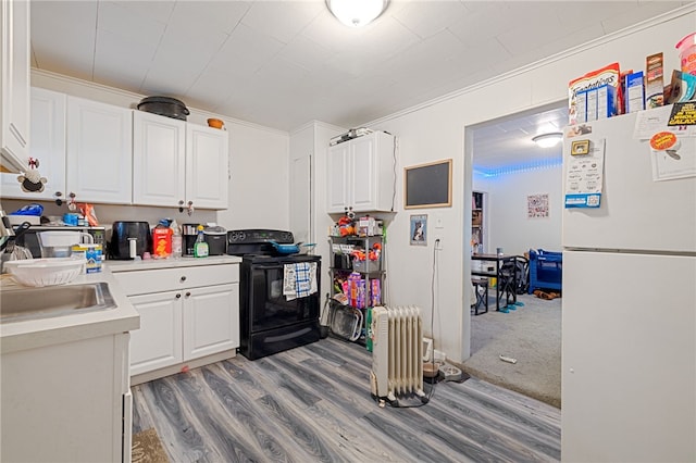 kitchen with white fridge, carpet flooring, black / electric stove, white cabinets, and radiator heating unit