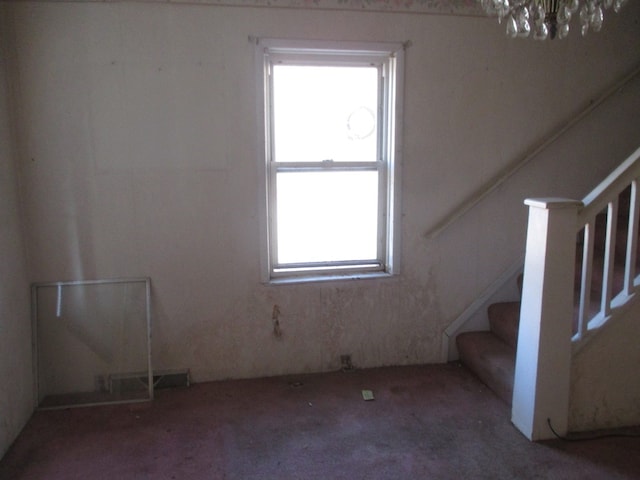 stairs featuring an inviting chandelier and dark carpet