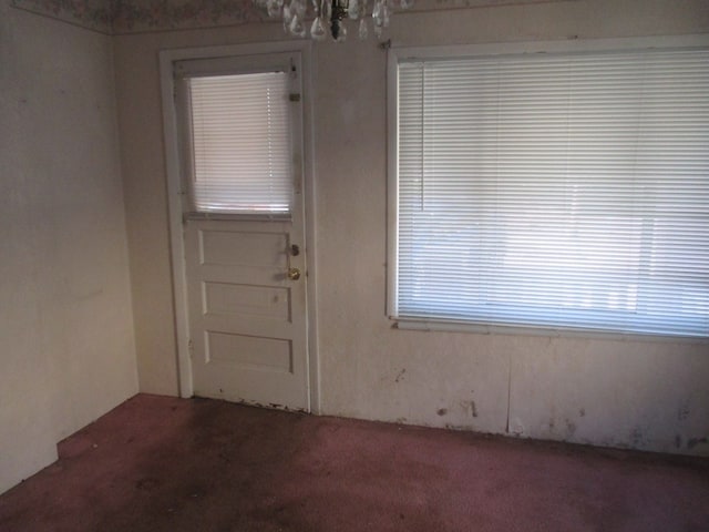 carpeted spare room with a notable chandelier