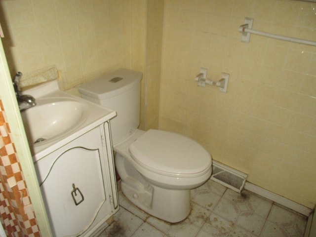 bathroom featuring tile flooring, toilet, tile walls, and vanity