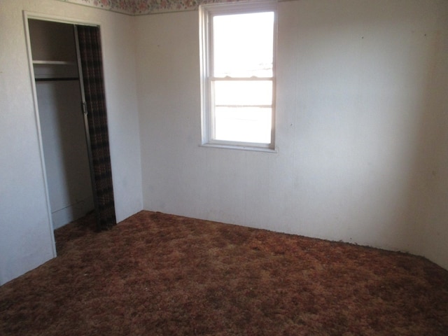 unfurnished bedroom featuring a closet and dark carpet