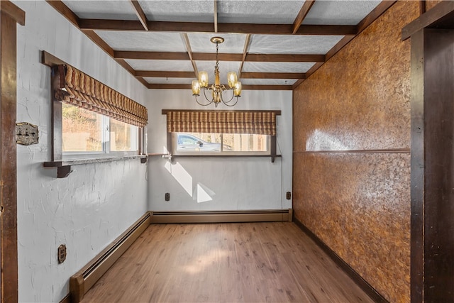 empty room featuring an inviting chandelier, light wood-type flooring, and beamed ceiling