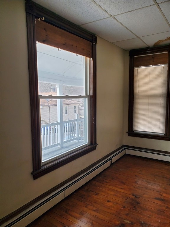 unfurnished room featuring a baseboard heating unit, a paneled ceiling, and dark hardwood / wood-style floors