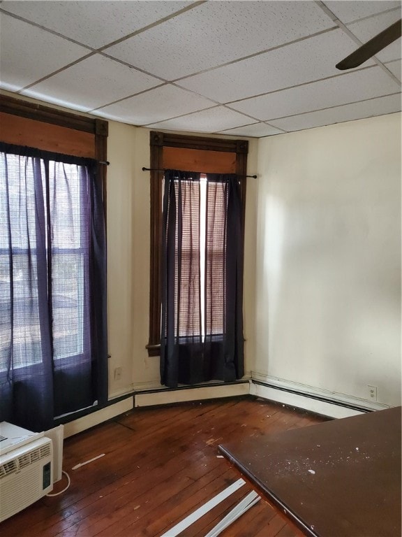 spare room featuring dark hardwood / wood-style flooring, ceiling fan, and a drop ceiling