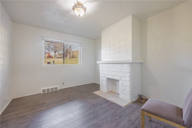 living room featuring dark hardwood / wood-style flooring and a brick fireplace