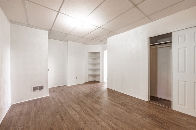 unfurnished bedroom with a closet, dark wood-type flooring, and a paneled ceiling