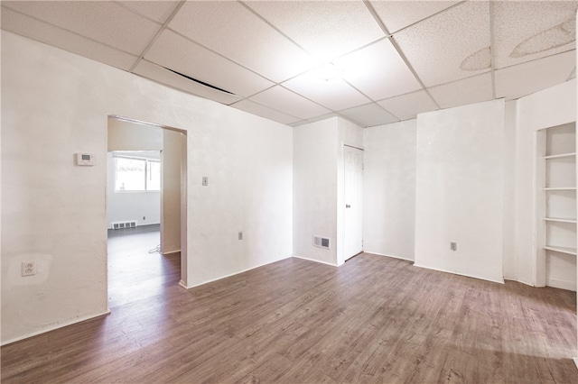 unfurnished room with a paneled ceiling and dark hardwood / wood-style flooring