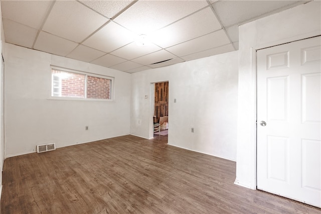 basement with a drop ceiling and dark wood-type flooring