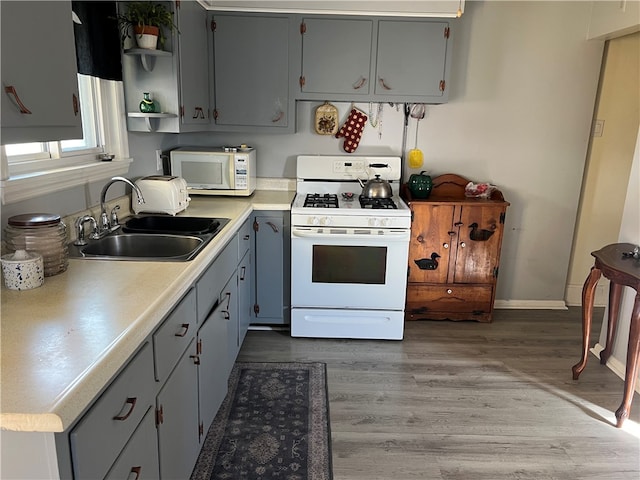 kitchen with gray cabinets, white appliances, sink, and dark wood-type flooring