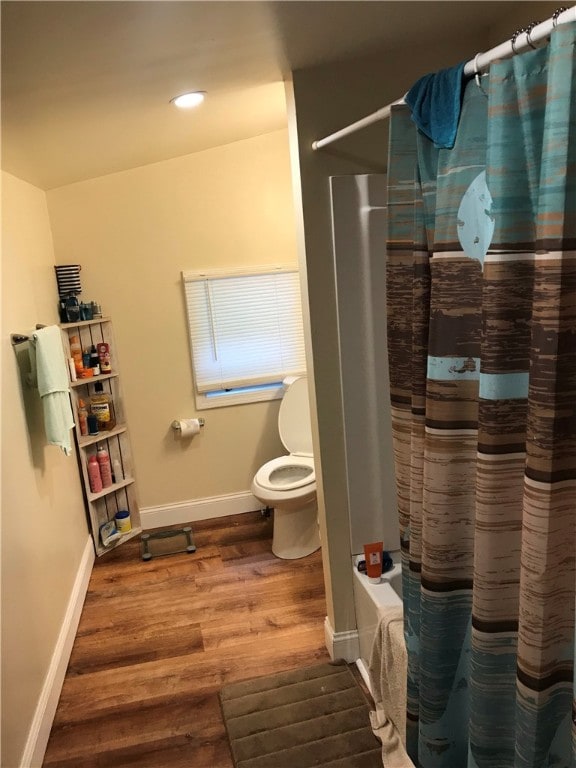 bathroom with toilet, shower / bathtub combination with curtain, and hardwood / wood-style flooring