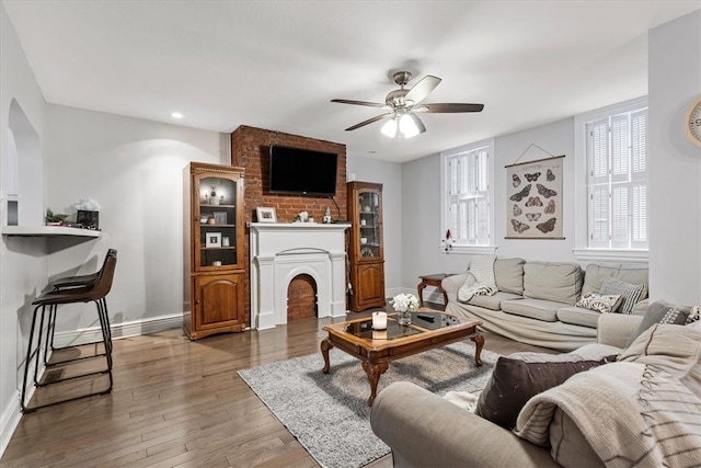 living room featuring brick wall, hardwood / wood-style floors, and ceiling fan