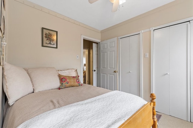 bedroom featuring two closets, light colored carpet, and ceiling fan