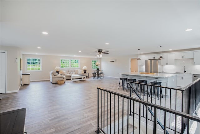 living room with sink, ceiling fan, and light hardwood / wood-style floors