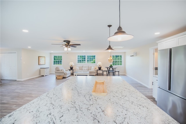 kitchen featuring white cabinetry, ceiling fan, hardwood / wood-style floors, light stone countertops, and stainless steel refrigerator