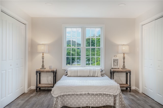 bedroom with multiple closets and dark hardwood / wood-style flooring