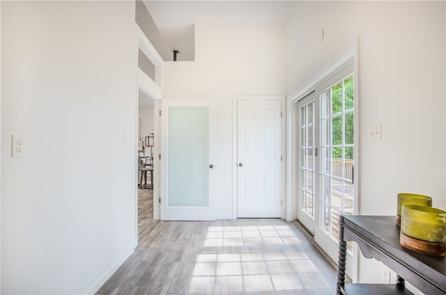 hallway featuring light hardwood / wood-style floors and a towering ceiling