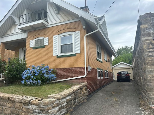 view of property exterior featuring a garage, an outdoor structure, and a balcony