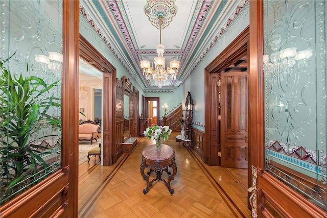 hall with light parquet flooring, crown molding, and an inviting chandelier