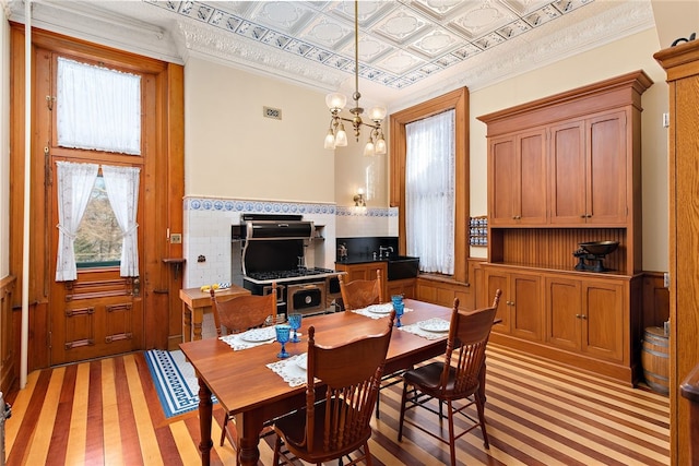 dining space with crown molding, a notable chandelier, and light wood-type flooring