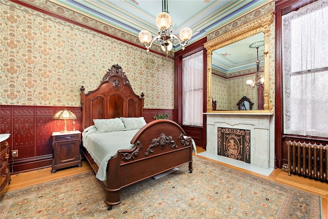 bedroom with radiator heating unit, light hardwood / wood-style flooring, a notable chandelier, and crown molding