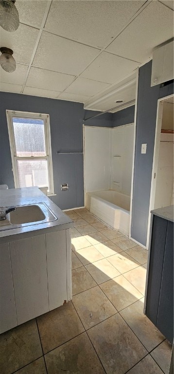 bathroom featuring sink, a drop ceiling, and tile floors