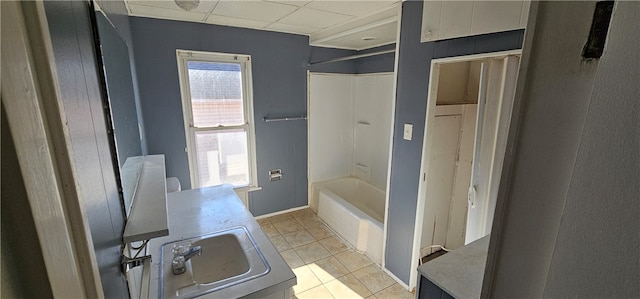 bathroom with a drop ceiling, tile floors, sink, and bathing tub / shower combination