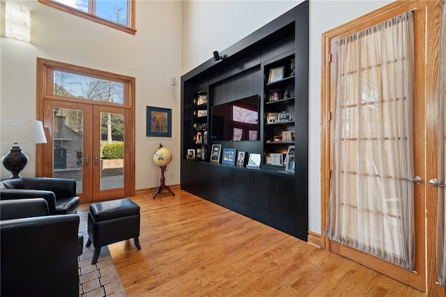 interior space featuring french doors, a towering ceiling, hardwood / wood-style floors, and a healthy amount of sunlight