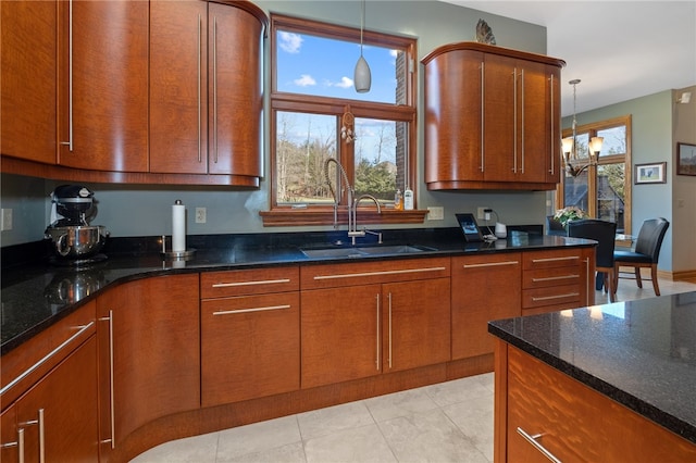 kitchen featuring dark stone countertops, light tile patterned flooring, an inviting chandelier, decorative light fixtures, and sink