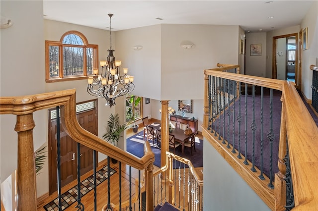 stairs with hardwood / wood-style floors and a chandelier