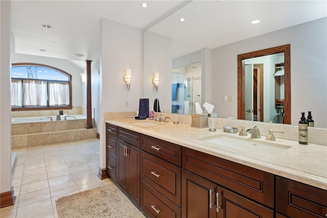 bathroom with tiled tub, vanity, and tile patterned flooring