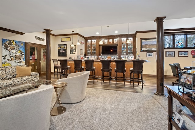 living room featuring ornamental molding, indoor bar, decorative columns, and wood-type flooring