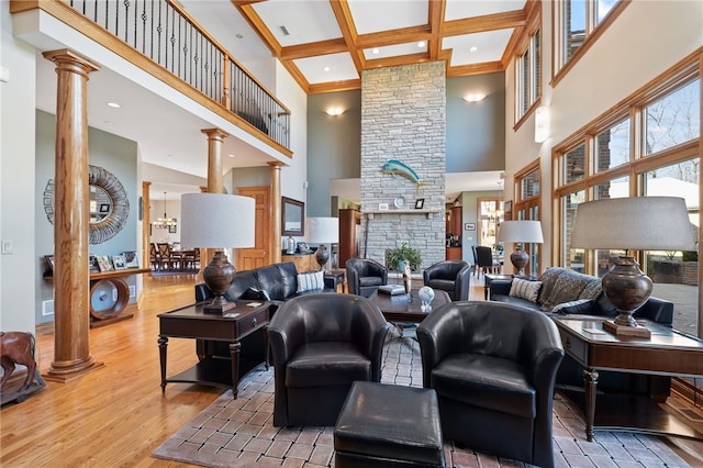 living room with beam ceiling, wood-type flooring, coffered ceiling, a towering ceiling, and ornate columns